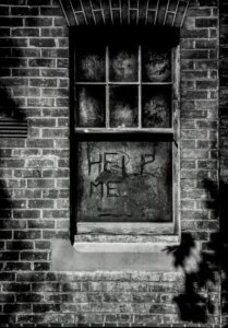 Dirty window with "Help me" written in the dirt